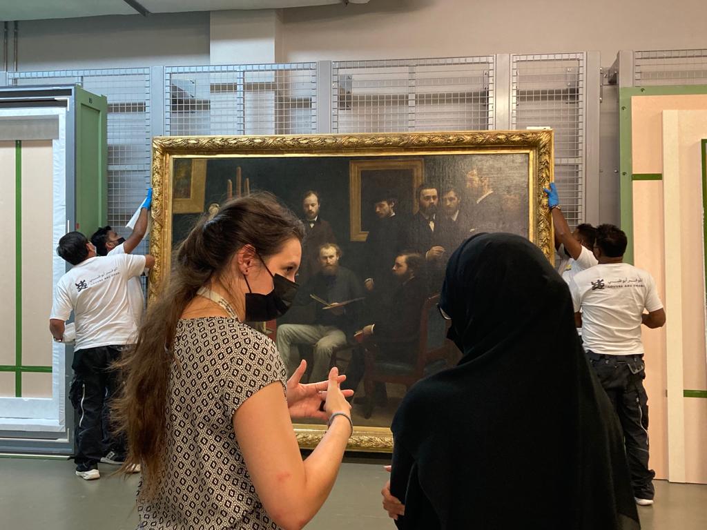 Two experts exchanging in front of a painting in Louvre Abu Dhabi storage unit Henri Fantin-Latour, Un atelier aux Batignolles - 1870. Capacity Building page
